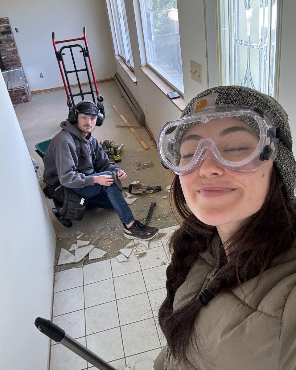 Kaylie in safety goggles while Jackson pulls up old floor tile